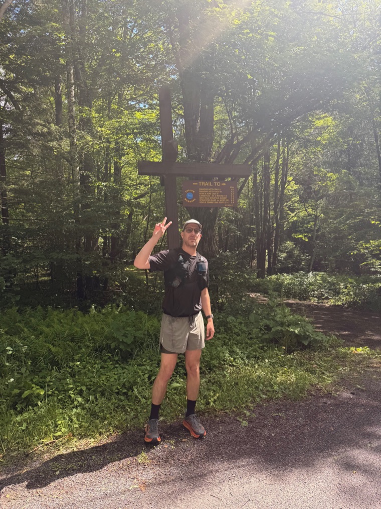 Matt Rubin throwing a peace sign at a trailhead in the Catskills at the start of a run